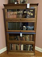 Front view of three-section oak barrister bookcase with printed top door and contents visible