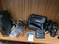 Overview of the lot showing Bushnell binoculars and their case, Pentax binocular case, LG receiver unit, and multiple cables.