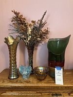 Full view of all items including three vases and two candle holders on wooden surface with dried flowers in one vase.