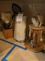Wide view of CutCo utensils in wooden block, paper towel holder, and lazy Susan with measuring utensils
