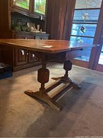 Side view of table with drop leaves up showing two turned pedestal bases and stretcher