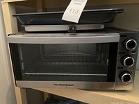 Full view of Hamilton Beach toaster oven with metal baking pans on top