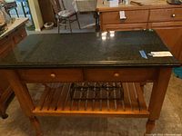 Front view showing granite top, wood base, two drawers, slatted shelf and wine rack