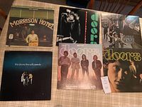 Six vinyl record albums by The Doors laid out on a table showing front covers including Morrison Hotel and The Soft Parade.