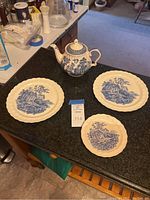 Photo showing the tea pot and three plates on a black countertop with kitchen background