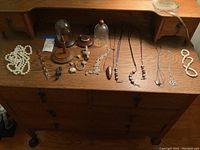 Dresser top with assortment of watches, necklaces, bracelets, ring