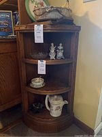 Full view of the wooden corner shelf placed in a room corner with various items on the shelves (not included in lot)