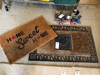 Two outdoor door mats, one with 'Home Sweet Home' design and one plain black mat.