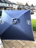 Square navy blue beach umbrella fully opened, showing top vent and fabric condition