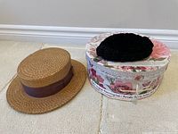 Dobbs men's boater straw hat and 1860s original mourning cap placed beside the floral hat box on carpeted floor.
