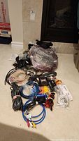 Overview of various cables including HDMI, RCA, power cords, wire coverings, and clamps laid out on carpet next to fireplace.