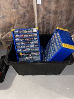 Overview of the two blue metal hardware organization cabinets inside a black plastic tote located in a basement