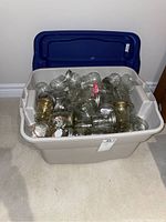 Photo of a large plastic storage tote filled with various clear glass canning and storage jars. Most jars have lids.