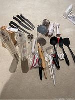 Overview of all kitchen items including knives, utensils, coffee grinder, mixer, and various kitchen tools arranged on a beige surface.