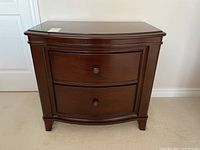 Front view of the solid wood night table showing the two curved front drawers with matching metal knobs and smooth finish.