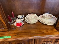 Photo showing the full set of Royal Albert fine bone china pieces including plates, bowls, and tea cups arranged neatly on a wooden shelf.