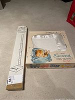 Esmond baby blanket box alongside Unique pin skirt hem marker box on carpet.