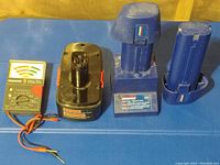 Photo showing battery tester, battery pack, and two battery charging stations.