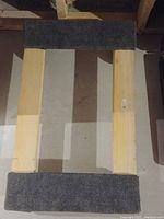 Top-down view of the wooden rectangular platform dolly with carpet padding on the narrow ends.