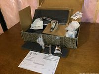 Opened box showing the Brizo faucet components including the spout, handles, and instruction manual.