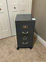Front view of gray metal file cabinet with two drawers and silver handles, with a sale sticker on top.