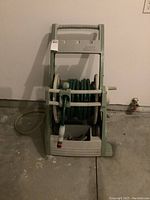 Front view of the hose reel with hose wound and attached spray nozzle visible.