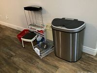 Photo of all items including the nine stars trash bin, dish racks, step stool, baskets, detergent and trays all arranged on floor.