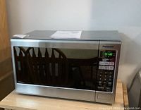 Full view of the stainless steel Panasonic microwave oven on a wooden surface.