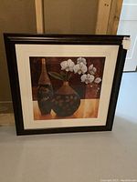 Full view of the matted and framed print showing two decorated vases and white orchids against warm background.