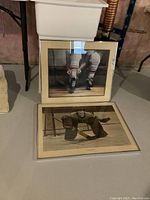 Two framed hockey prints boxed and placed on floor, one stacked on the other showing hockey scenes