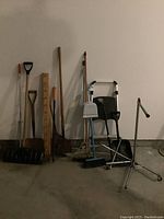 Full view of all garden and cleaning tools, and step ladder arranged against a wall