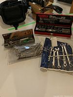 Overview of all tools including two socket sets and two sets of wrenches laid out on surface