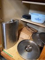 Metal flask, metal lids, brown paper bags and part of cookware shelving