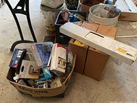 Wide view showing unopened boxes, plastic bins with electrical items, and long white box containing transformer.