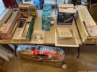 Photo of table with packaged lighting items, air vents, and garage door opener box visible.