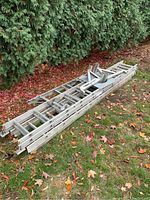 View of two aluminum extension ladders and five aluminum step ladders laid on grass showing condition and size