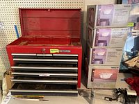 Front view of red Craftsman tool chest with open drawers and top lid showing storage compartments, with cards attached showing lot numbers