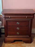 Full front view of wooden 5 drawer side table with brass and oval metal drawer pulls, showing its reddish-brown wood finish and carved base.