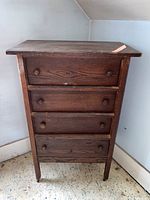 Front view of the chest showing the four drawers closed, all with round wooden knobs and visible wood grain.