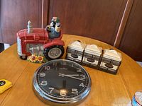Wall clock, ceramic canisters set, and tractor cookie jar shown side by side on table.