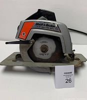 Front and side view of Black & Decker circular saw showing blade and body with visible brand and model details.