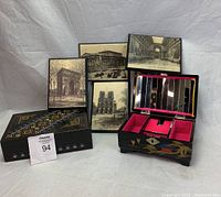 Two open decorative boxes, one showing velvet interior with foldable mirror and five framed black and white architectural wall art pieces behind them
