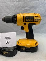 DeWalt 18V cordless drill with two rechargeable batteries placed on surface against a plain background.