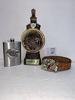 Photo showing the Alaska flask, Ruidsoso Downs horse-shaped bottle, and Lady Luck belt with buckle and embossed leather figures along the strap.