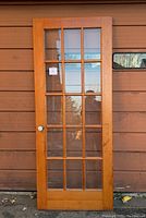 Full view of the wooden French door showing its glass panes and overall condition.