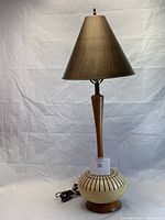 Full view of the mid-century modern table lamp showing the bronze shade, wooden stem, and ceramic base with black vertical lines.
