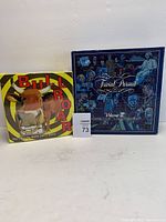 Photo of two party game boxes, Bull Roar (left) and Trivial Pursuit Volume II (right), with lot tag 73.