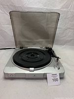 Full view of silver record turntable with clear dust cover open, showing the platter and controls.