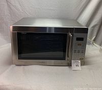 Front view of Sanyo stainless steel microwave oven showing door, handle, and keypad panel.