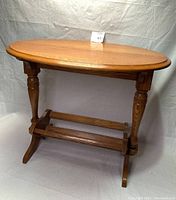 Full view of the wooden side table showing the oval tabletop and supporting legs.